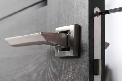 Repairing door handle with screwdriver indoors, closeup