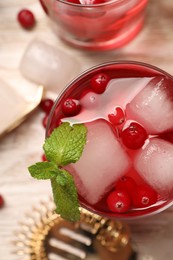 Photo of Tasty cranberry cocktail with ice cubes and mint in glasses on light table, flat lay