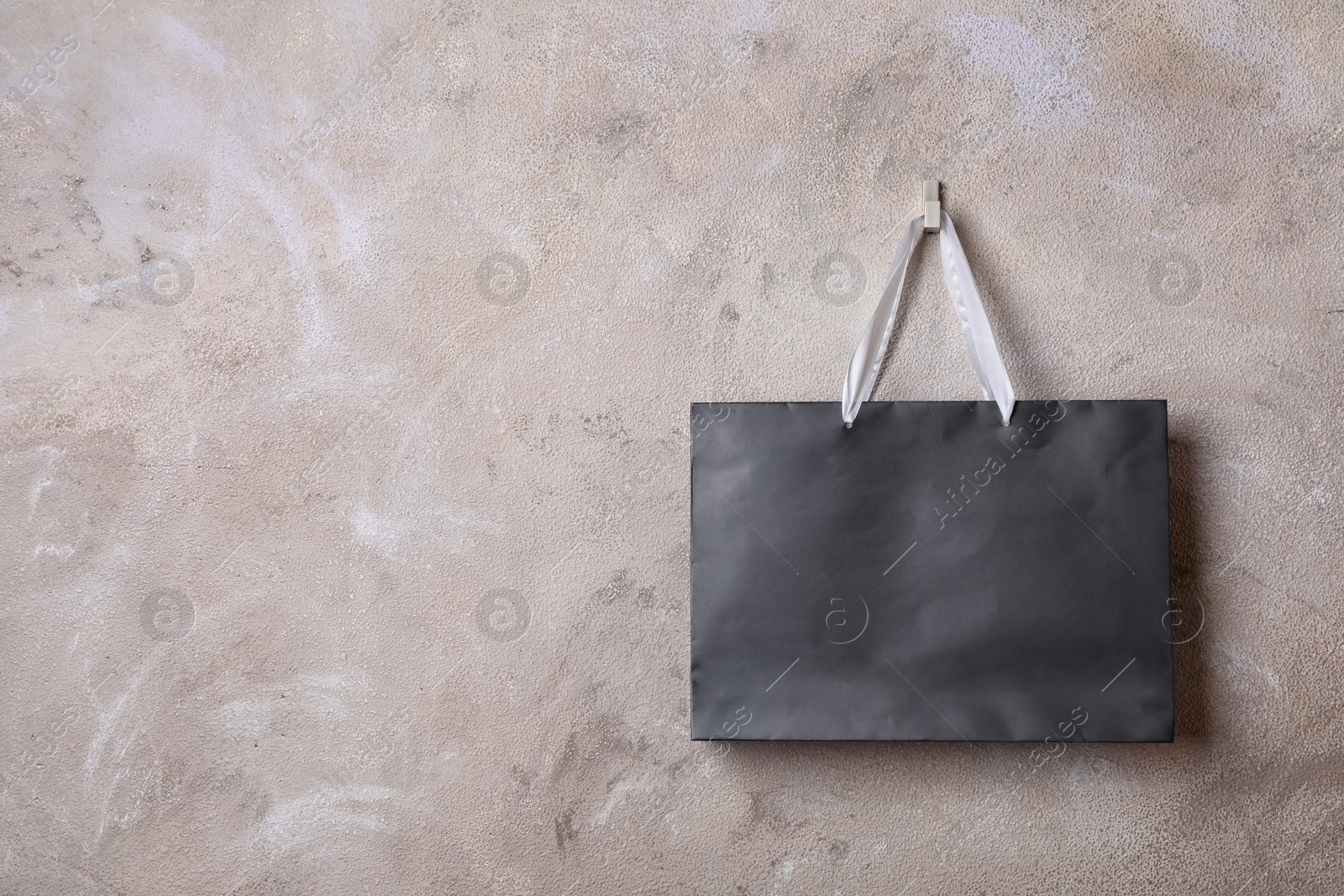 Photo of Paper shopping bag with handles hanging on color wall. Mock up for design