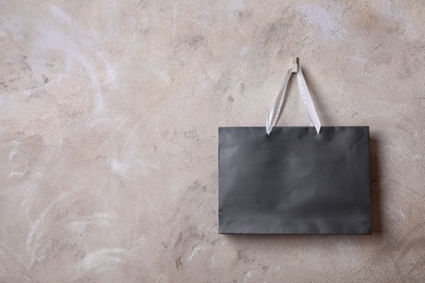 Photo of Paper shopping bag with handles hanging on color wall. Mock up for design