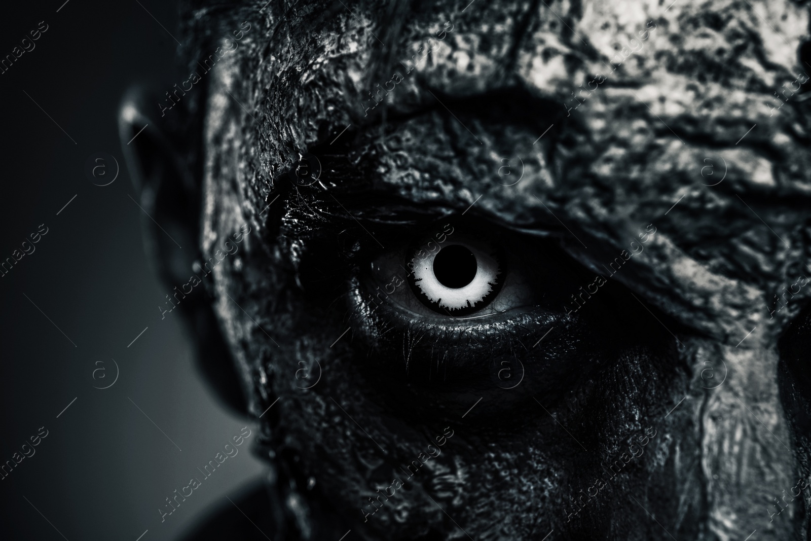 Photo of Closeup view of scary zombie on dark background, black and white effect. Halloween monster