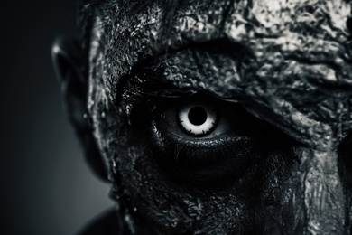 Closeup view of scary zombie on dark background, black and white effect. Halloween monster