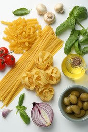 Different types of pasta, spices and products on white background, top view