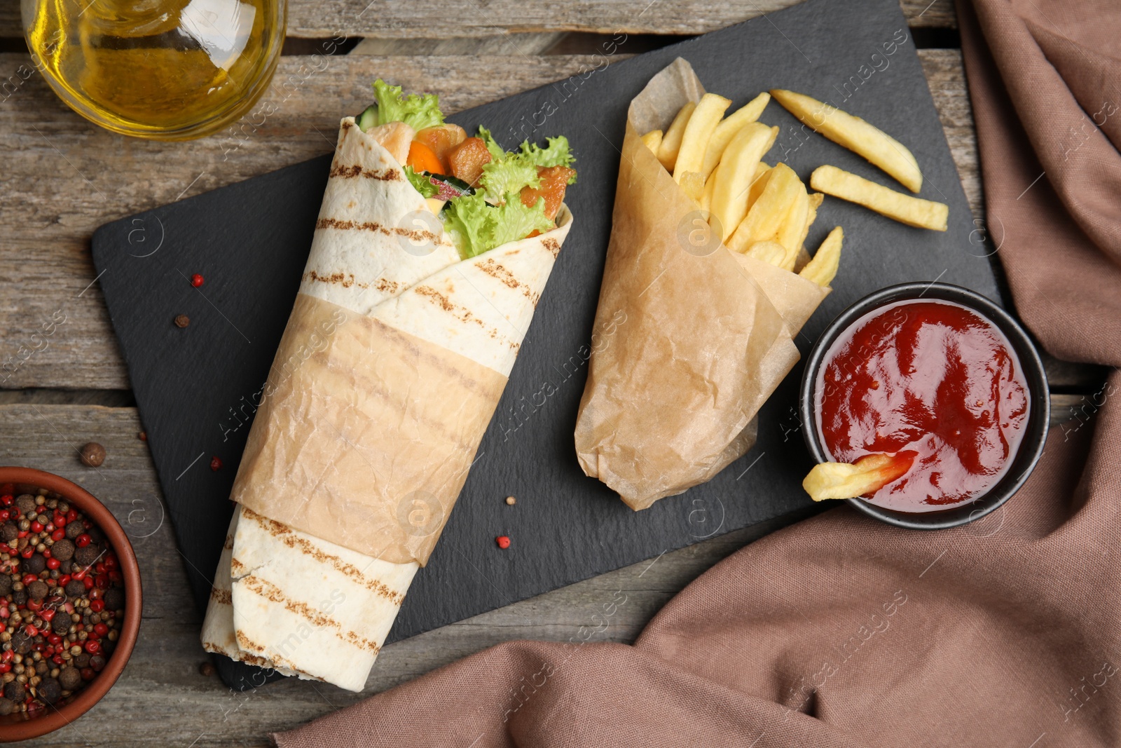 Photo of Delicious chicken shawarma and French fries served on wooden table, flat lay