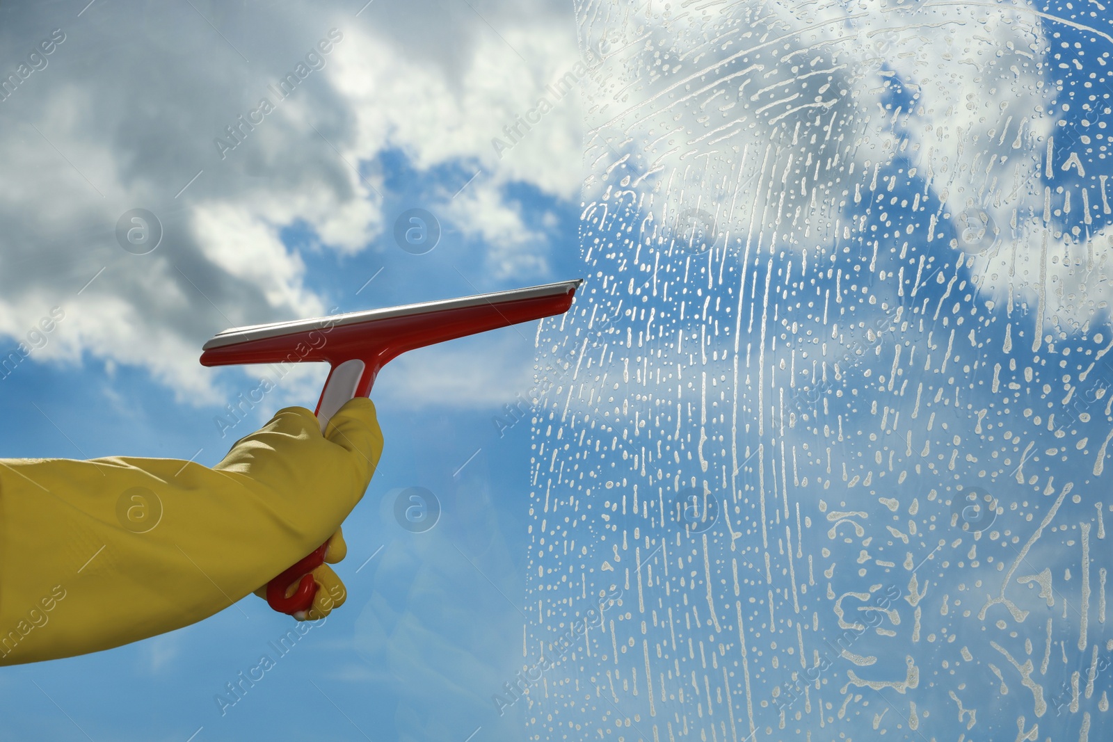 Photo of Woman cleaning glass with squeegee indoors, closeup