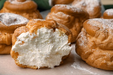 Delicious profiteroles filled with cream on parchment paper, closeup