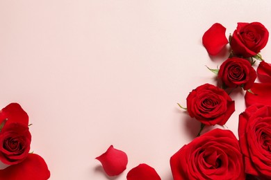 Photo of Beautiful red roses and petals on pale pink background, flat lay. Space for text