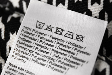 Photo of Clothing label with care symbols and material content on shirt, closeup view