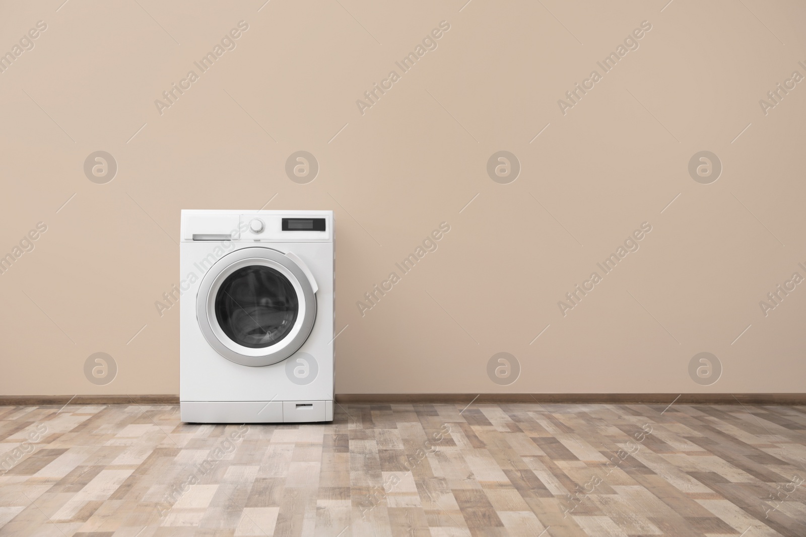 Photo of Modern washing machine with laundry near color wall, space for text