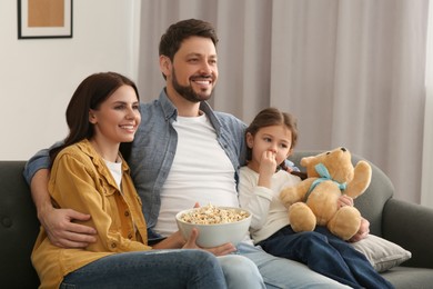 Happy family watching TV on sofa at home