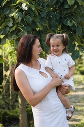 Happy mother with her cute daughter spending time together in park