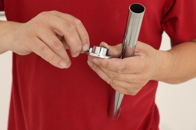 Photo of Worker holding metal tube and pipe fitting for installation, closeup