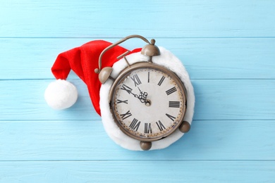 Photo of Alarm clock and Christmas decor on light blue wooden background, top view. New Year countdown