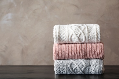 Photo of Stack of folded knitted sweaters on table. Space for text