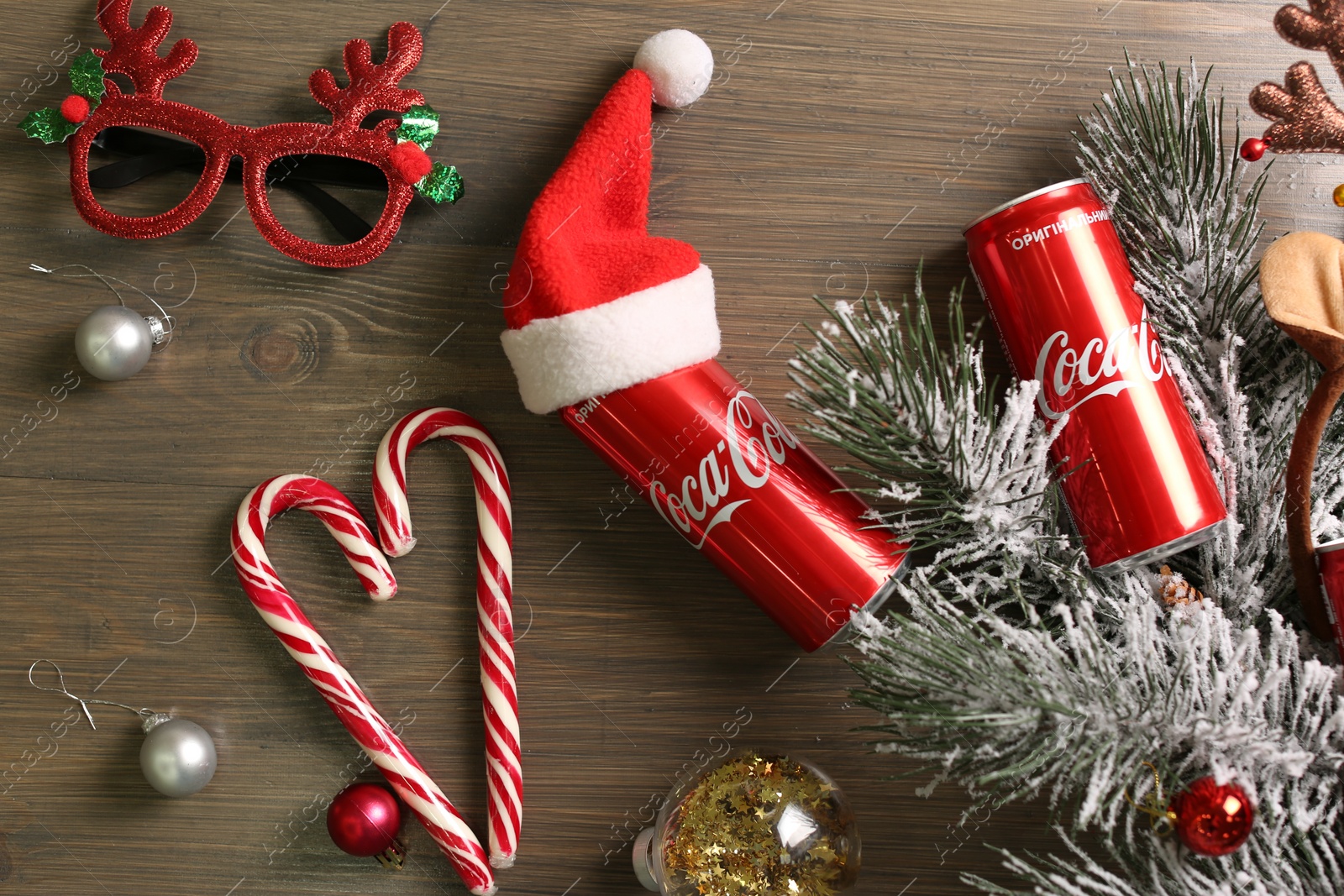 Photo of MYKOLAIV, UKRAINE - January 01, 2021: Flat lay composition with Coca-Cola cans and Christmas decorations on wooden background