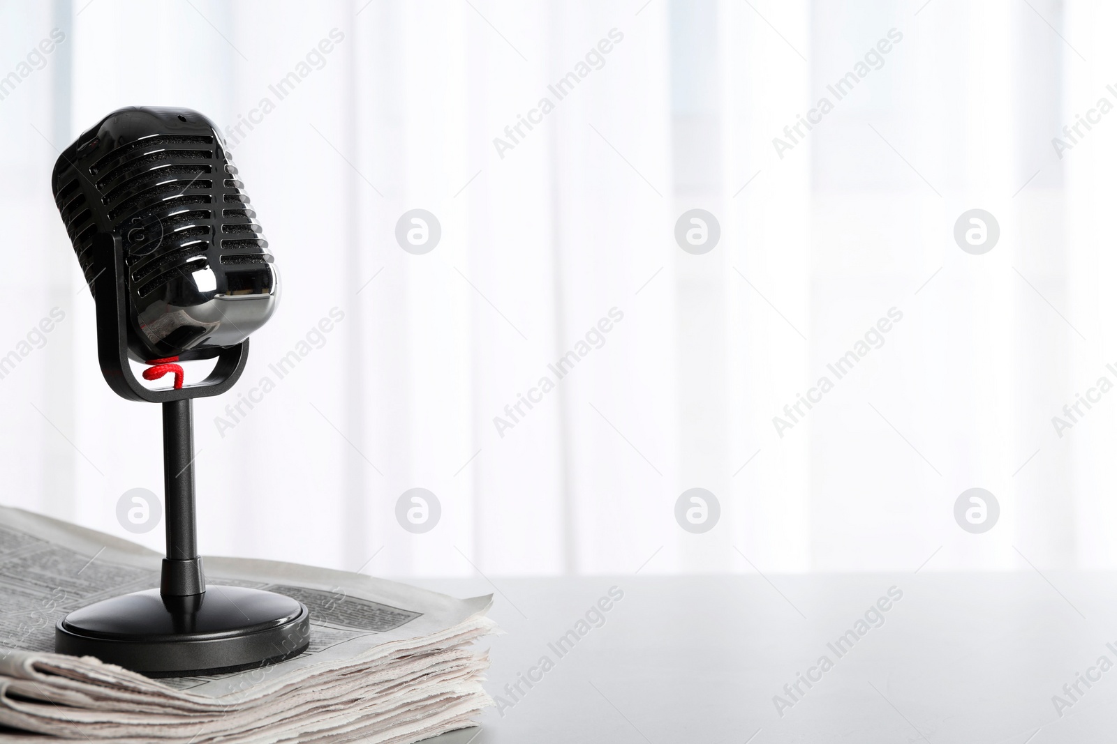 Photo of Newspapers and vintage microphone on grey table, space for text. Journalist's work