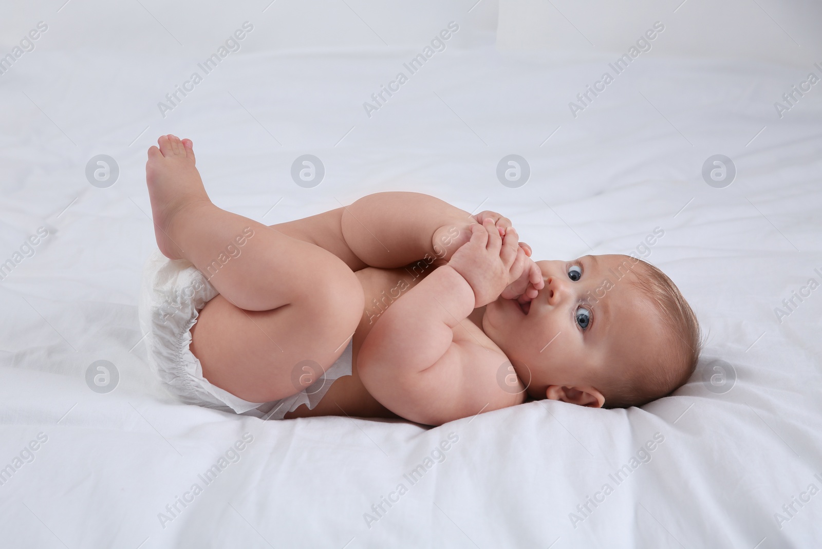 Photo of Cute baby in dry soft diaper on white bed