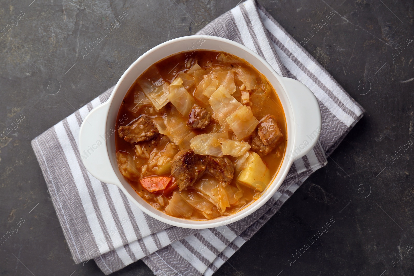 Photo of Tasty cabbage soup with meat and carrot on grey table, top view