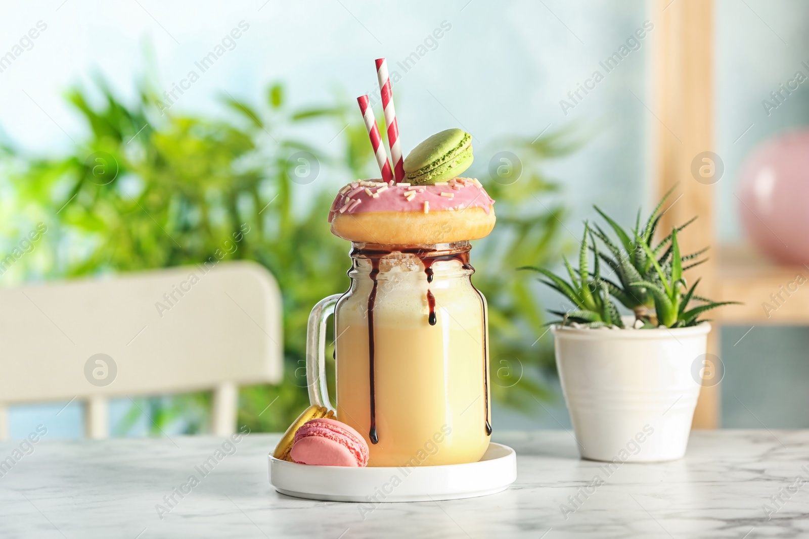 Photo of Mason jar with delicious milk shake on table against blurred background