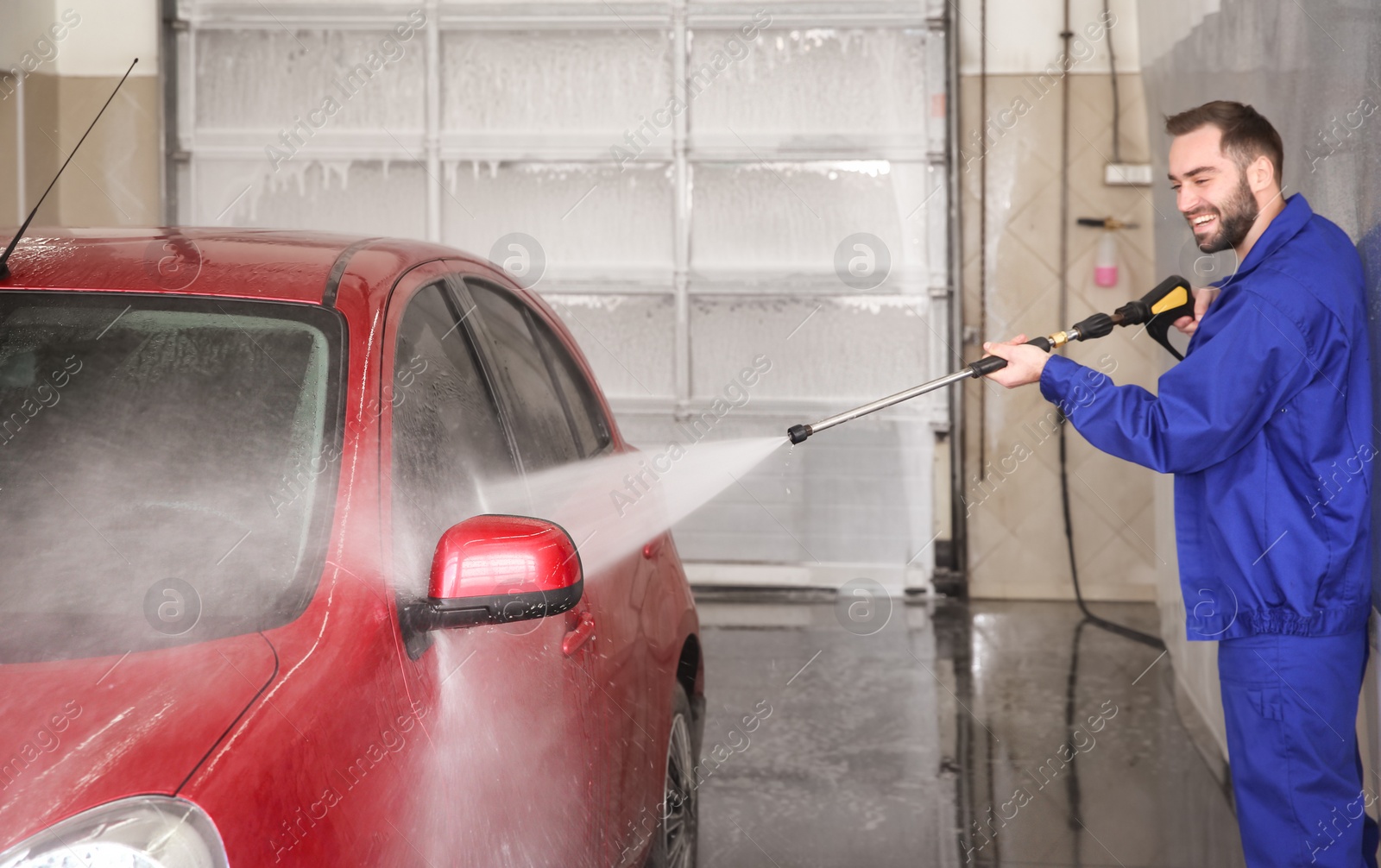 Photo of Worker cleaning automobile with high pressure water jet at car wash