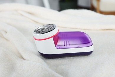 Modern fabric shaver on beige cloth indoors, closeup