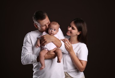 Happy family with little baby on dark background