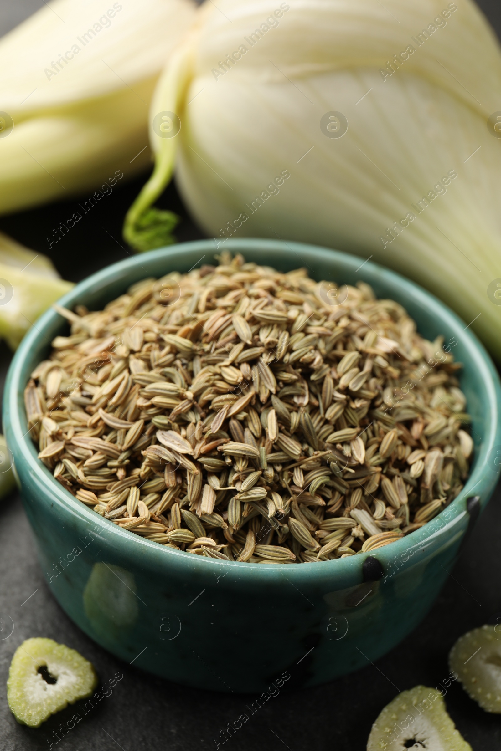 Photo of Fennel seeds in bowl, whole and cut vegetables on table, closeup