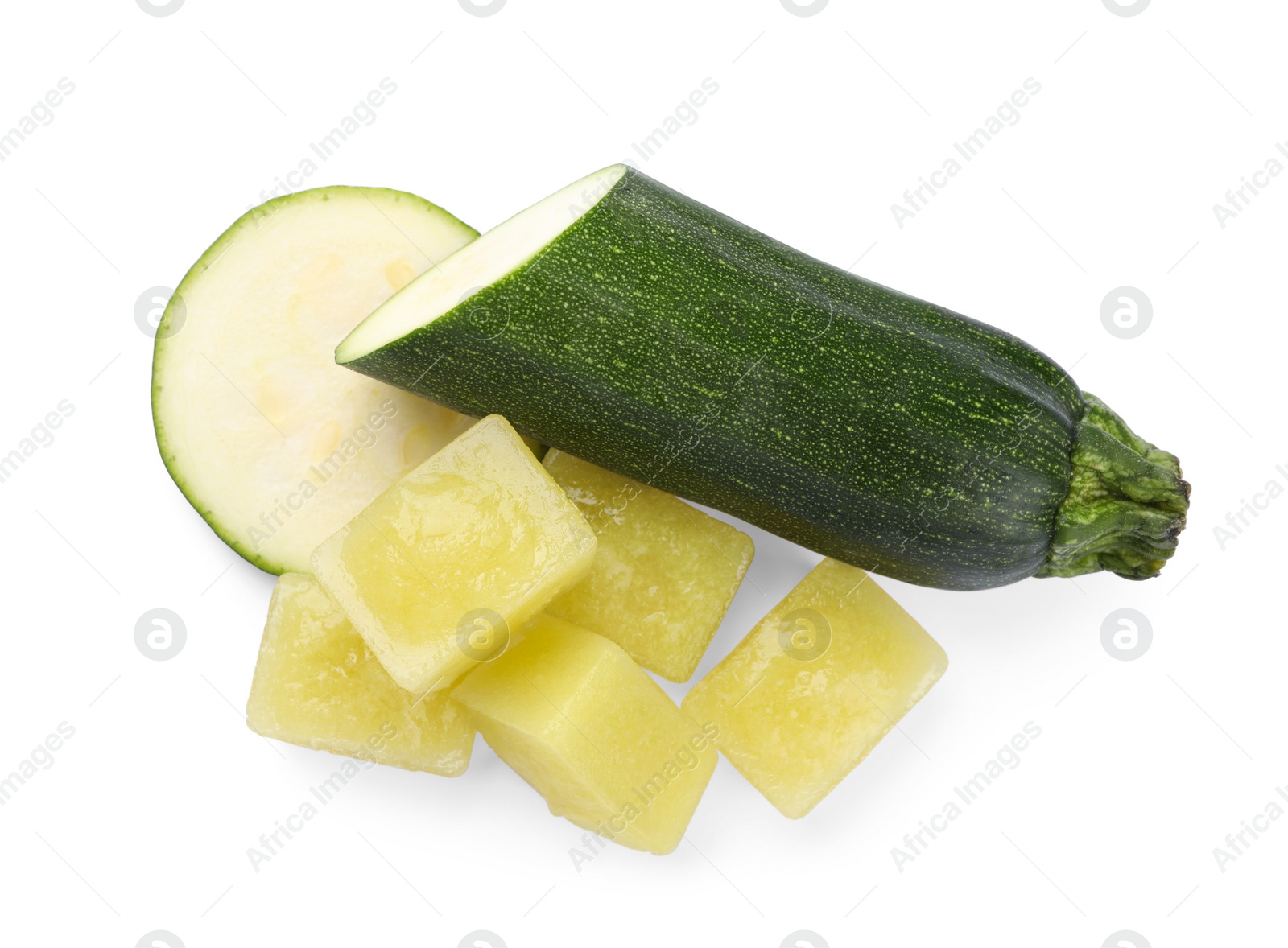 Photo of Frozen zucchini puree cubes and fresh zucchini isolated on white, top view