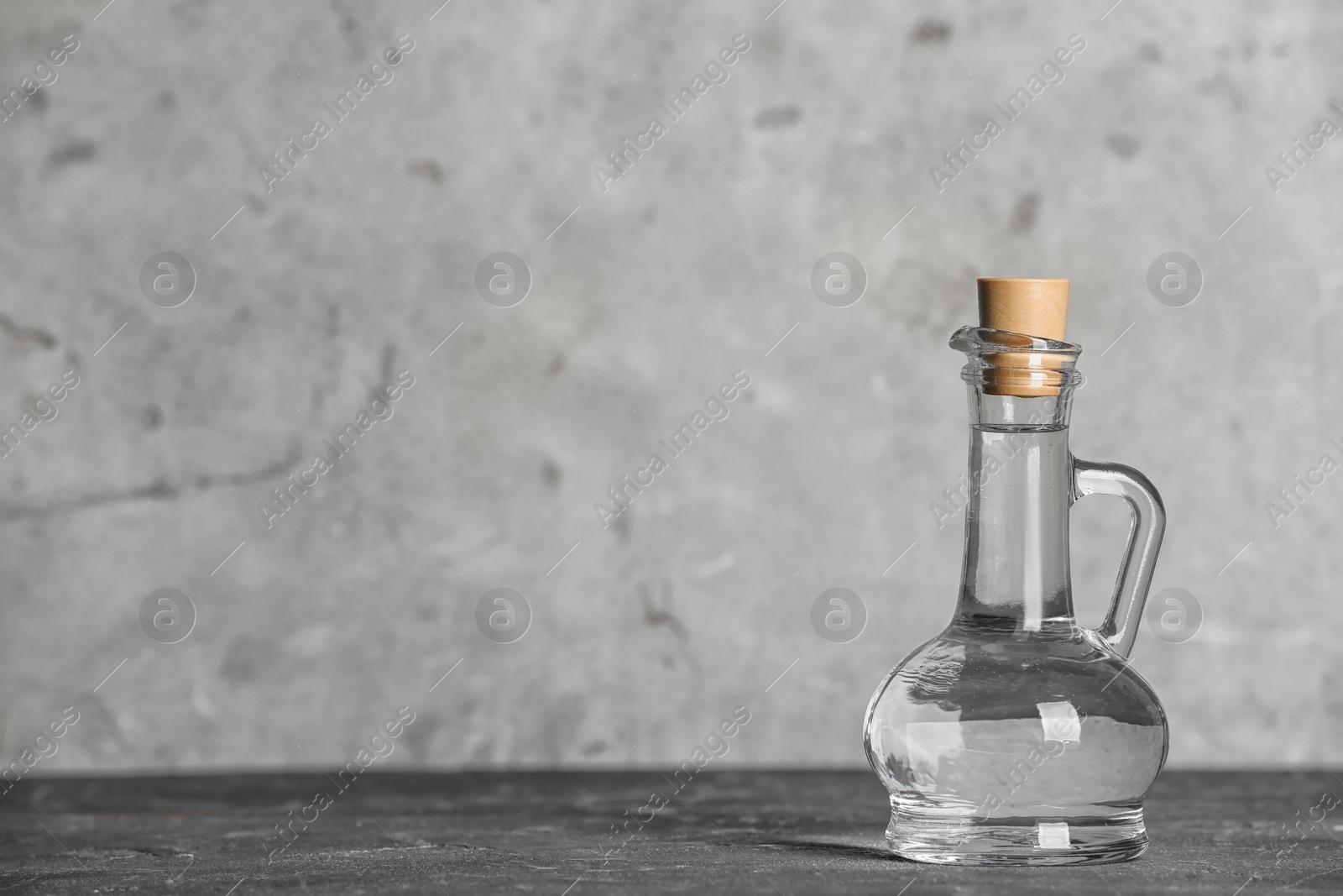 Photo of Glass jug with vinegar on table. Space for text