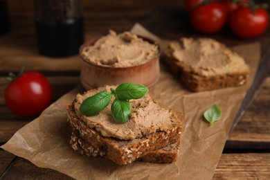 Photo of Fresh bread with delicious meat pate and basil served on wooden table, closeup