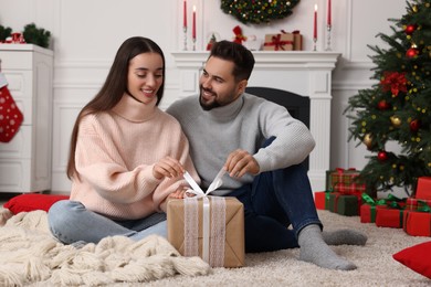 Happy young couple opening Christmas gift at home