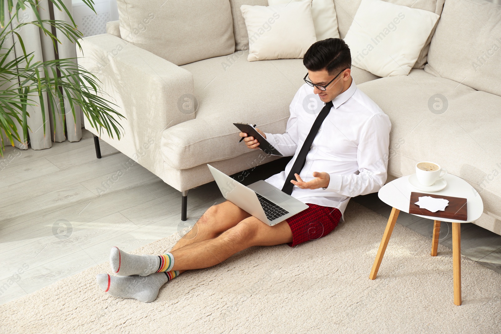 Photo of Businessman in shirt and underwear having video call on laptop at home