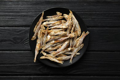 Delicious dried anchovies on black wooden table, top view