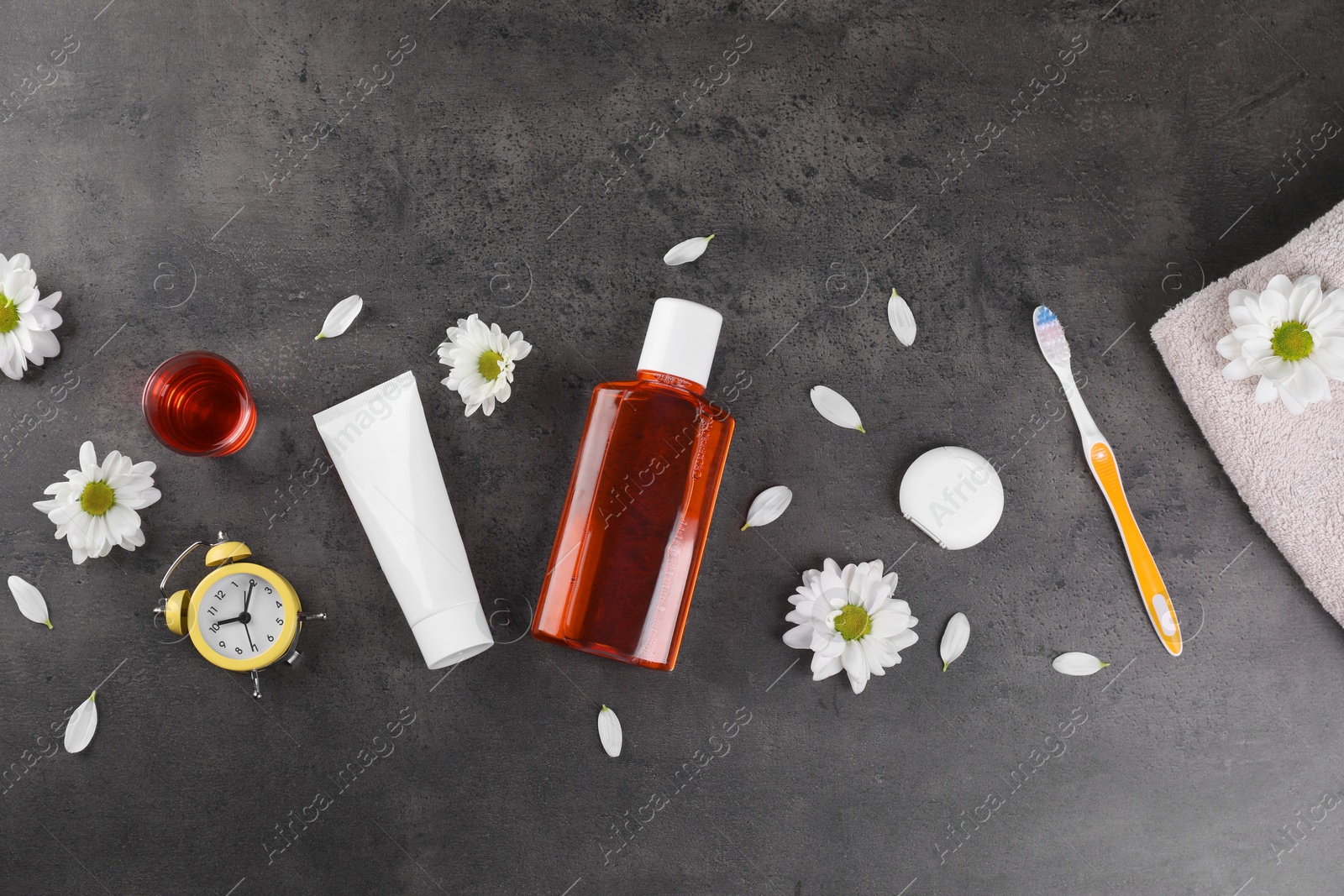 Photo of Fresh mouthwash and other oral care products on dark textured table, flat lay