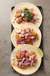 Delicious tacos with vegetables, meat and lime on grey textured table, top view