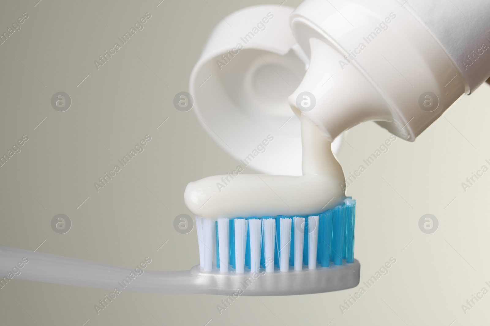 Photo of Applying paste on toothbrush against light background, closeup