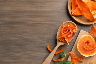 Photo of Dry orange peels on wooden table, flat lay. Space for text
