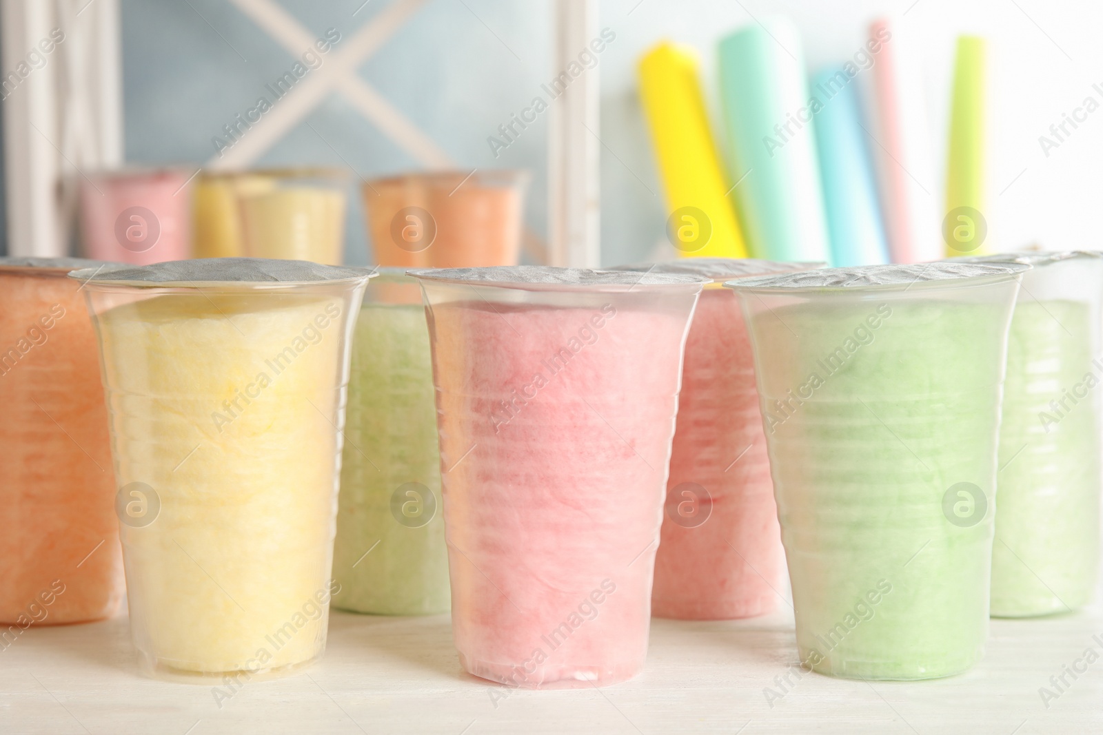 Photo of Plastic cups with cotton candy on table against blurred background