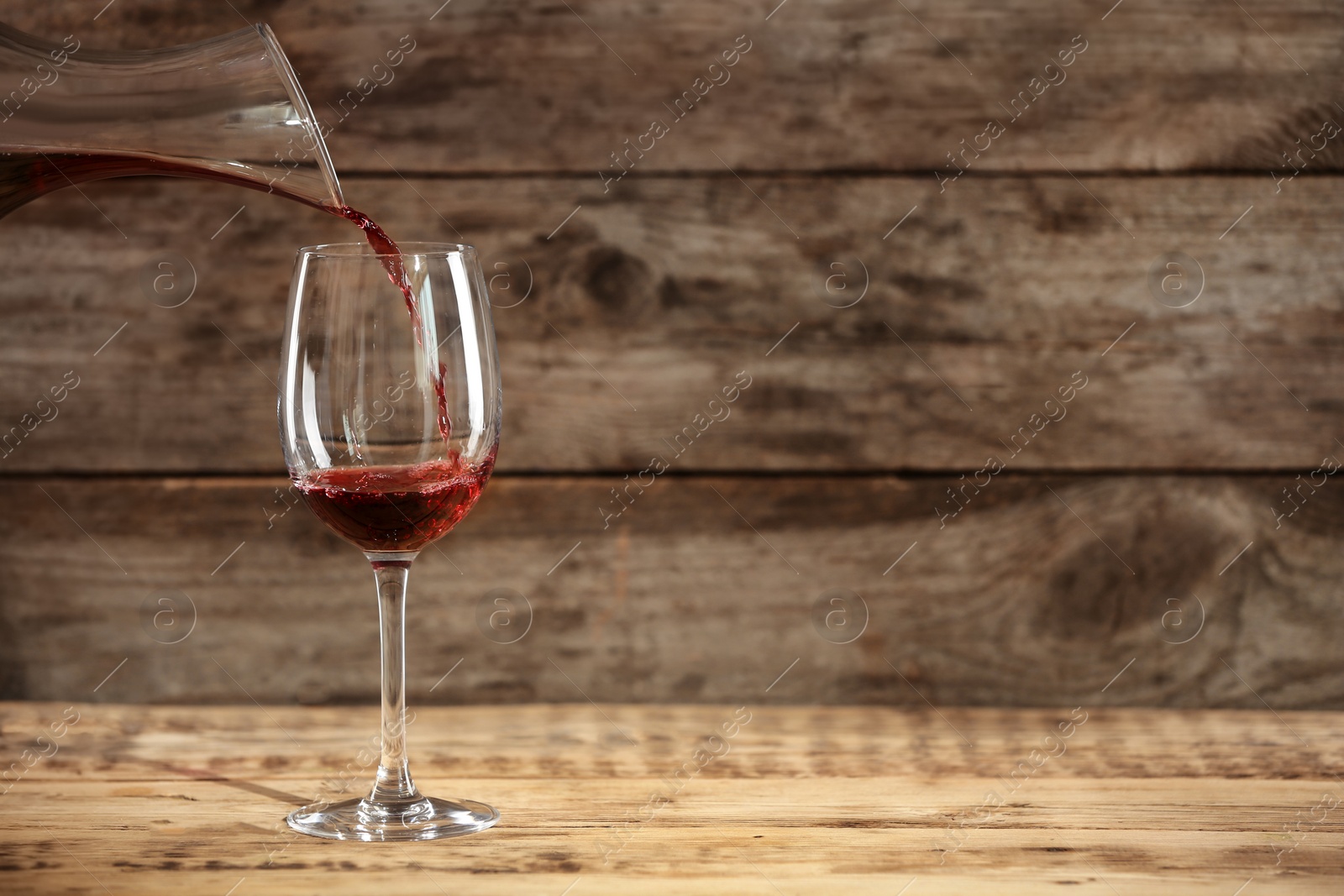 Photo of Pouring delicious red wine into glass on table