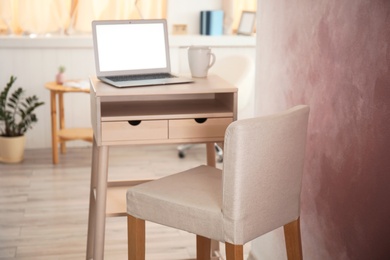 Photo of High wooden table with laptop as stand up workplace in modern interior