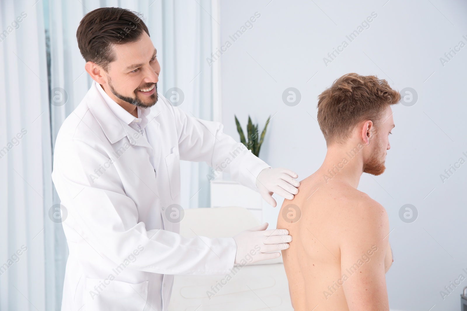 Photo of Dermatologist examining patient's birthmark in clinic