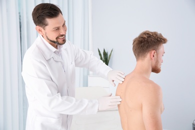 Dermatologist examining patient's birthmark in clinic