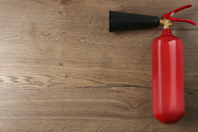 Photo of Fire extinguisher on wooden background, top view. Space for text