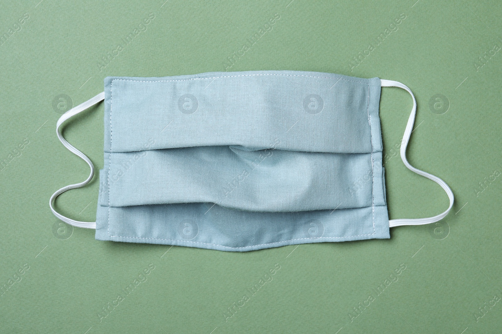 Photo of Homemade protective mask on gray-green background, top view. Sewing idea