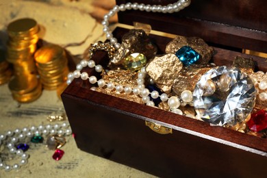 Photo of Chest with treasures and scattered sand on floor, closeup