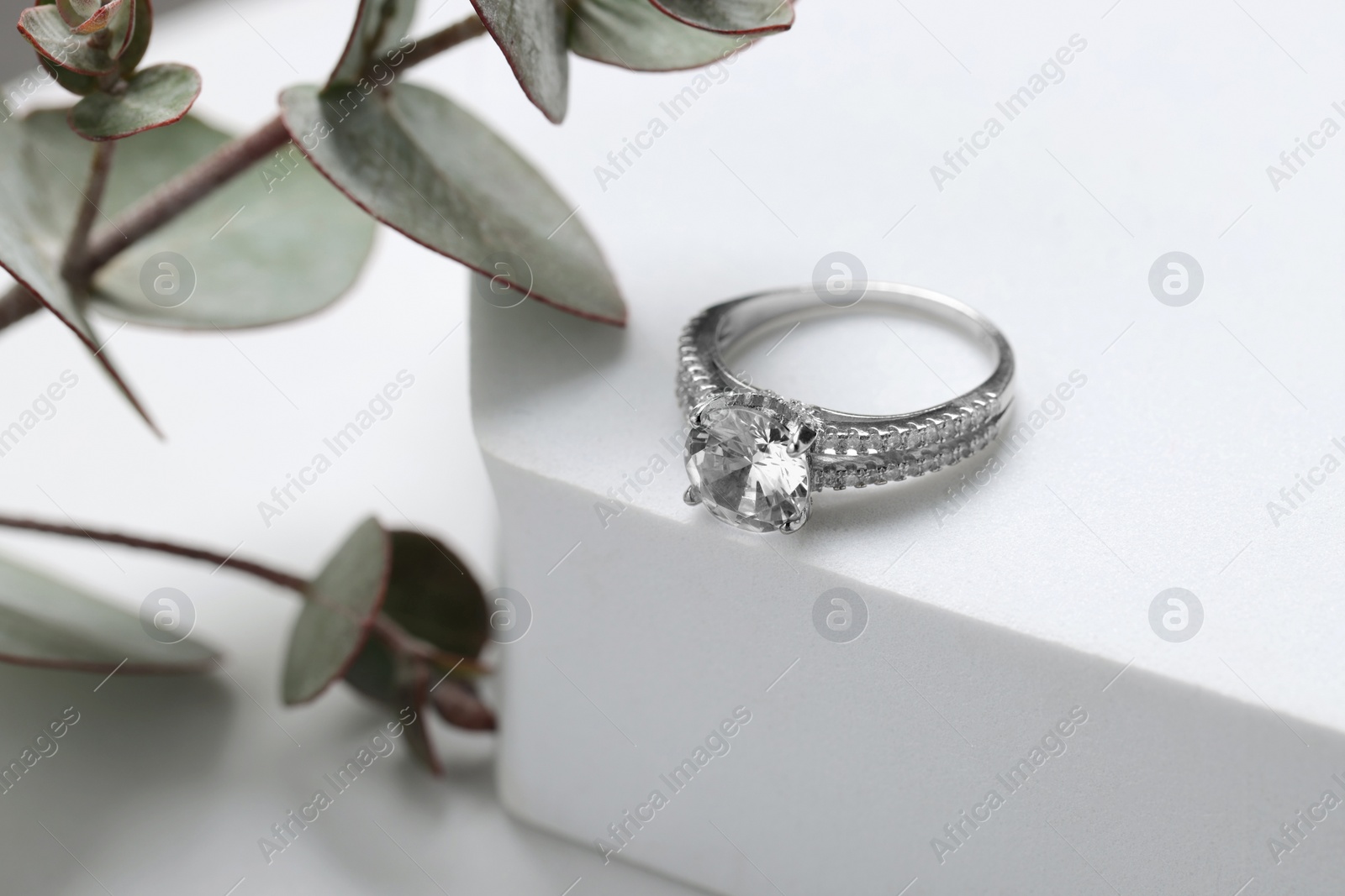 Photo of Beautiful ring with gemstones on white podium. Luxury jewelry