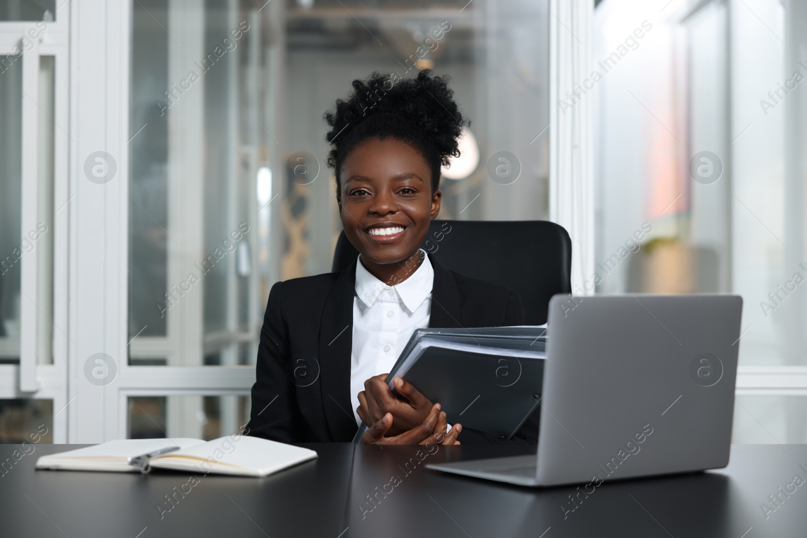 Photo of Happy woman with folders working at table in office. Lawyer, businesswoman, accountant or manager