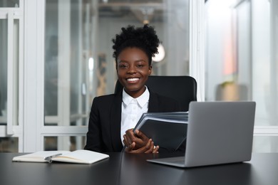 Photo of Happy woman with folders working at table in office. Lawyer, businesswoman, accountant or manager