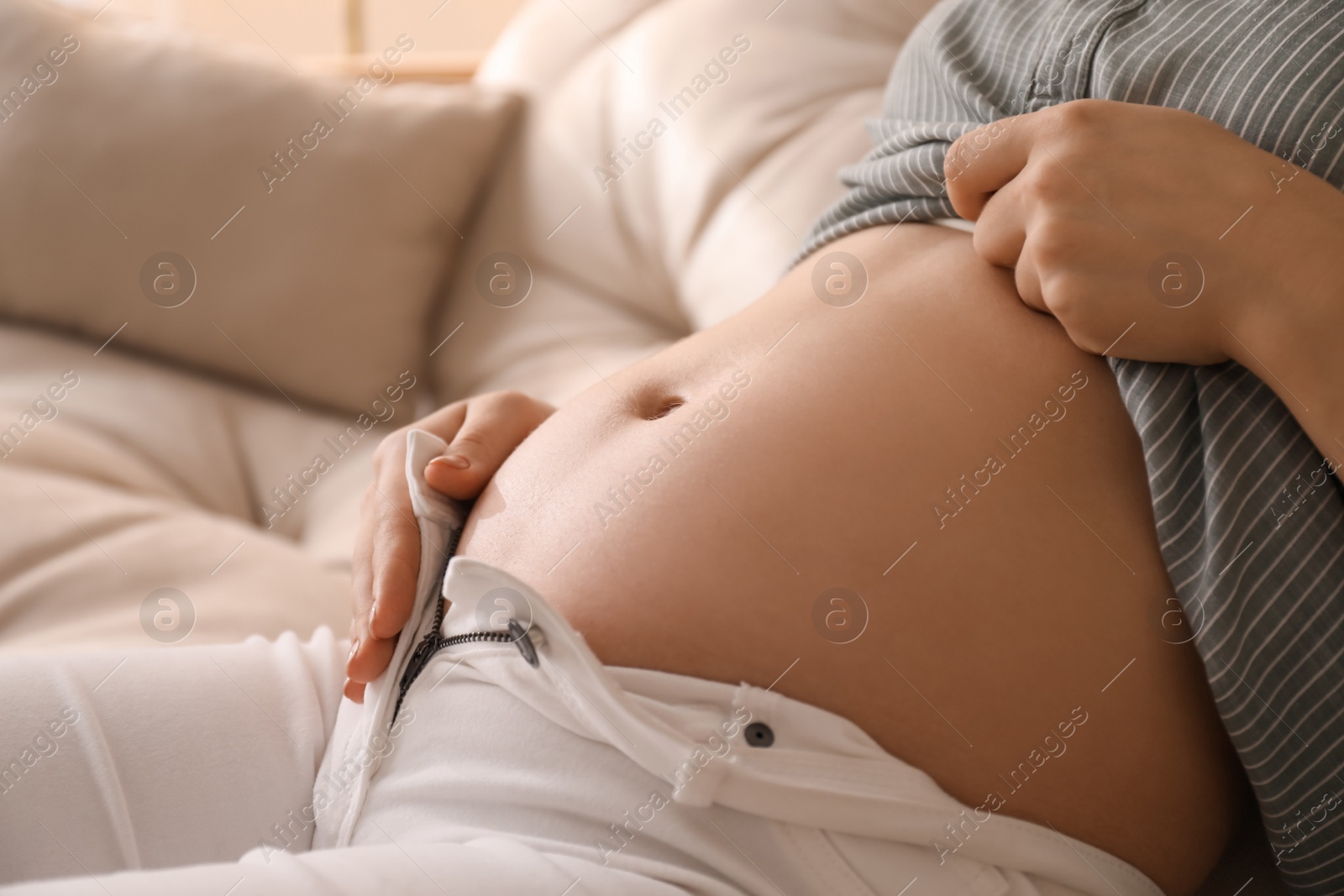 Photo of Pregnant young woman touching belly at home, closeup