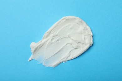 Photo of Smear of delicious cream cheese on light blue background, top view